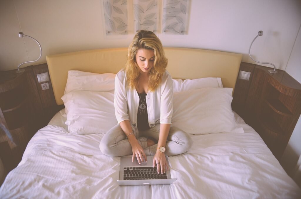 Mujer trabajando en un portátil sobre la cama